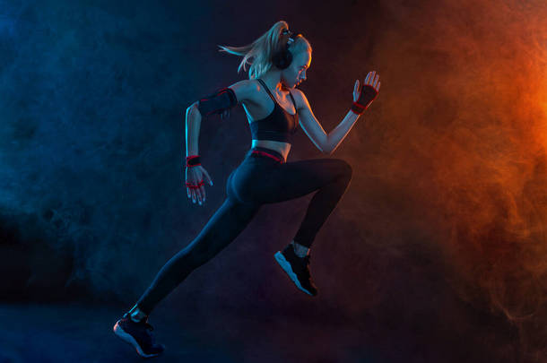 斯普林特跑强壮的女运动员穿着<strong>运动服</strong>,穿着黑色的背景跑步.健身和运动动机。跑步者概念.