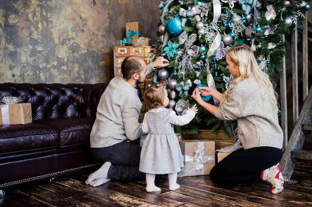 父母们在家里装饰圣诞树。家庭、圣诞节、寒假和人的概念。有孩子的家庭庆祝寒假. 
