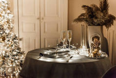 浪漫温馨舒适的夜晚在圣诞客厅室内设计中，圣诞树装饰灯饰花环照明节日。除夕之夜，餐桌眼镜装饰香槟酒