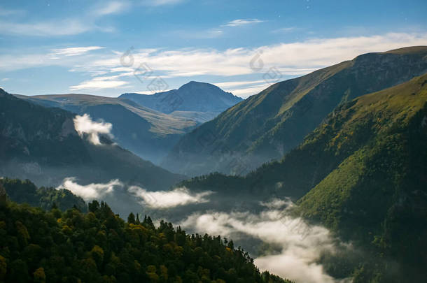 高山峡谷有雾，岩石峰背景，蓝天有云和星星。山地景观。夜间以慢速<strong>快门</strong>速度拍照