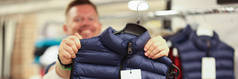 在商店的特写镜头里，微笑的男人拿着新的保暖背心