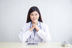 美丽的亚洲女医生坐在她办公室的办公桌前。医院医疗服务的概念病人的治疗和保健