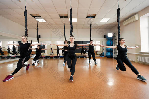 一群身穿黑色运动服的活跃的女运动员在体育馆里做体操。蹦极跳进体育馆.