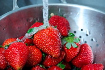新鲜的草莓新鲜的清晰的水溅从成熟的<strong>红</strong>色的草莓<strong>不锈钢</strong>钢滤器与水滴抓住了暂停的空气