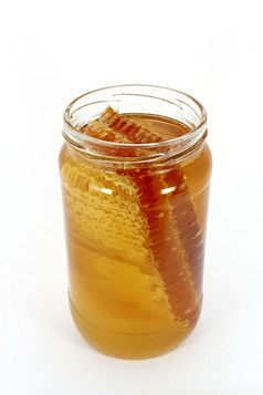 玻璃jar完整的蜂蜜与蜂窝孤立的白色