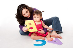 妈妈。保姆老师教学快乐婴儿学习字母与信好玩的道路而坐着地板上