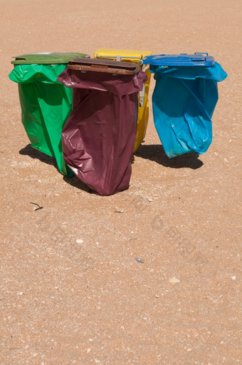 四个色彩斑斓的回收垃圾箱海滩