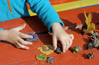 孩子玩在户外的图像部分小孩子玩与橡皮泥的街后面红色的木桌子上孩子戏剧与粘土而且各种各样的自然材料与不同的形状