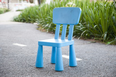 蓝色的塑料椅子位置的地板上而且走的公园后面的灌木