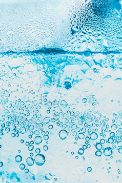 透明的背景苏打水水和冰与明亮的蓝色的泡沫在的玻璃摘要