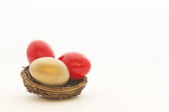 两个红色的鸡蛋和一个黄金蛋巢反映重要的选<strong>择业</strong>务和投资复制空间白色背景