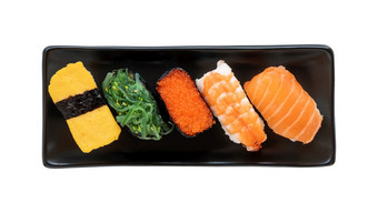 日本寿司食物黑色的板牧和尼吉里与大马哈鱼虾陪客海藻和tomago前视图各种各样的寿司孤立的白色背景