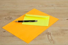 橙色纸和黄色的信封与黑色的笔