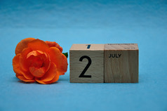 7月木块与橙色玫瑰蓝色的背景