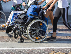 禁用运动员体育运动轮椅在马拉松帮助女跑步者禁用运动员体育运动轮椅在马拉松帮助女跑步者