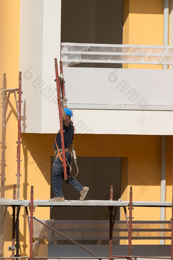 工人与蓝色的需要戴安全帽的工作脚手架建筑网站为的建设建筑工人与蓝色的需要戴安全帽的工作脚手架建筑网站为的建设建筑