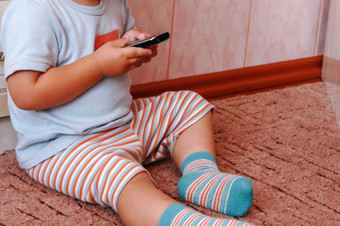 婴儿男孩玩与移动电话的首页数字技术的手孩子