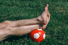 光着脚腿足球球男人。说谎草场户外白天夏天一天健康的生活方式概念