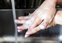 年轻的高加索人女人洗她的手与肥皂正确的手在的左手保持手清洁个人哪