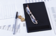 黑色的平板电脑鲁奇卡和眼镜说谎的金融表和图金融会计销售预测图分析
