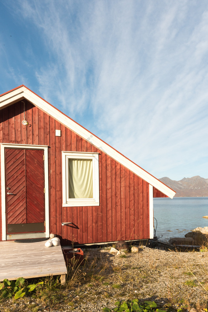 关闭裁剪视图木挪威海滩小屋与石头的海岸线