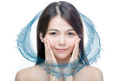 中国人女人与蓝色的水飞溅护肤品概念