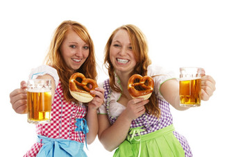 两个巴伐利亚女孩与椒盐卷饼欢呼与啤酒两个巴伐利亚女孩与椒盐卷饼欢呼与啤酒白色背景