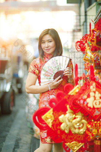 亚洲女人穿中国人传统衣服与中国人竹子风扇露出牙齿的微笑脸耀华力街中国小镇曼谷泰国