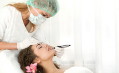 健康水疗中心特写镜头美丽的放松年轻的女人有面部按摩电解与兰花长棕色（的）头发