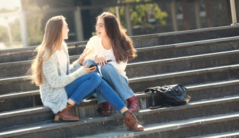 两个快乐女青少<strong>年会</strong>说话的在一起的街坐着的楼梯