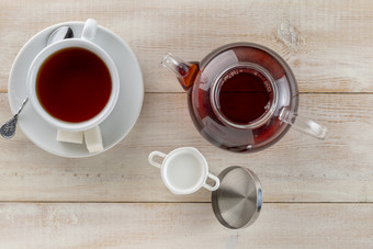 玻璃茶壶杯子热黑色的茶和牛奶壶木表格玻璃水壶茶杯热黑色的茶和牛奶壶木桌面视图