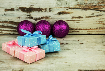 四个彩色的包圣诞节礼物老木表格和的背景三个紫色的闪闪发光的装饰物浅深度场水平视图