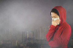 女人与流感打喷嚏女人穿着粉红色的冬天服装穿面具她的鼻子冷和流感健康概念对有毒灰尘覆盖的城市曼谷有健康效果曼谷空气污染