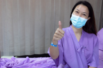 年轻的亚洲女病人微笑和显示拇指手势病人感觉快乐和舒适的与治疗和治疗医院床上医院房间医疗医疗保健概念医疗医疗保健概念