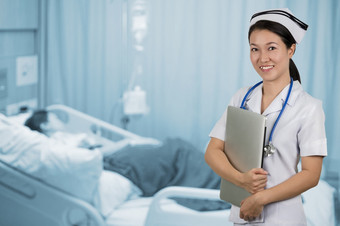 亚洲护士持有笔记本与背景模糊病人房间亚洲护士