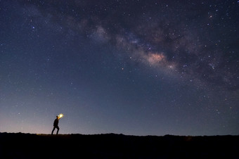 软焦点登山者与火的手岩石山峰找到的目标搜索下的<strong>星星</strong>和乳白色的道路星系晚上成功赢家领袖概念高iso与噪音领袖前