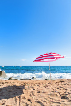 空海滩与波海和条纹粉红色的阳伞