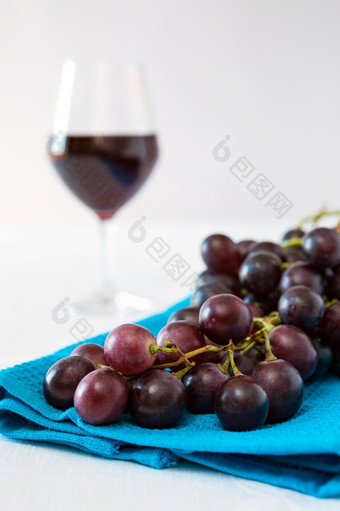 特写镜头群红色的葡萄和玻璃红色的酒背景在蓝色的桌布特写镜头群红色的葡萄和玻璃红色的酒背景