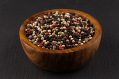 碗各种各样的胡椒花椒种子混合黑色的石头