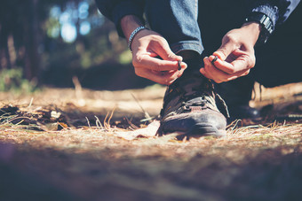 年轻的徒步旅行者男人。关系的鞋带他的鞋在假期徒步旅行森林年轻的徒步旅行者男人。关系的鞋带他的鞋在假期回来