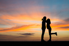 轮廓年轻的夫妇爱享受好时间在一起在轮廓年轻的夫妇爱享受好时间在一起在日落