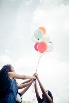 快乐集团女孩朋友手持有五彩缤纷的气球