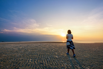 年轻的女人旅游漫步的海滩看的美丽的自然景<strong>观色</strong>彩斑斓的的天空和的海在日落纳通日落的<strong>观</strong>点寒这封信他尼府泰国女人漫步的海滩日落