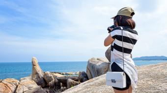 年轻的女人是使用数码单反相机相机摄影的欣欣Yai和美丽的自然景观蓝色的海和天空在夏天旅行KOH寒岛这封信他尼府泰兰女人采取照片的欣欣Yai