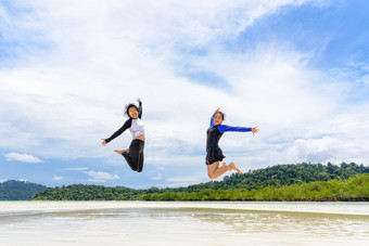 快乐两个亚洲青少年女孩朋友跳享受的海滩蓝色的天空背景在的海之旅假期夏天假期利普岛塔鲁陶国家公园satun泰国两个亚洲青少年女孩朋友跳享受的海滩