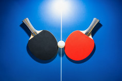 前视图黑色的和红色的表格网球球拍和白色平发出难闻的气味球的蓝色的平发出难闻的气味表格与明亮的关注的焦点两个表格网球桨体育竞争设备为室内锻炼前视图黑色的和红色的表格网球球拍