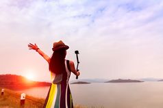 旅行者女人享受取自拍美丽的日落的湖与山背景