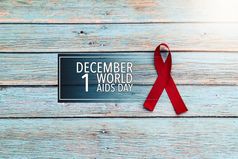 世界健康一天艾滋病意识标志红色的丝带的战斗对艾滋病标志的蓝色的木背景
