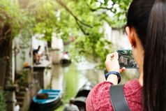 年轻的女人有有趣的当地的运河城市中国与相机智能手机使图片