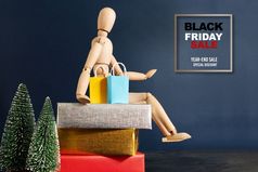 黑色的星期五出售木娃娃坐着礼物盒子与购物袋和圣诞节树